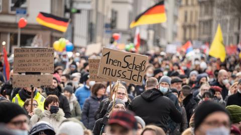 Eine Frau trägt ein Plakat mit der Aufschrift "1nen Scheiß muss ich" bei einer Demonstration von mehreren tausend Menschen gegen Corona-Maßnahmen und Impfpflicht in der Frankfurter Innenstadt.