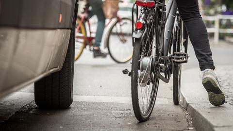 Radfahrer stehend neben Auto.