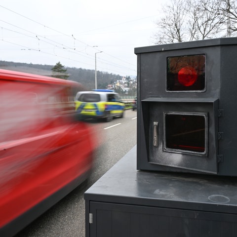 Autos fahren auf einer Straße an einem Blitzer zur Geschwindigkeitskontrolle vorbei. 