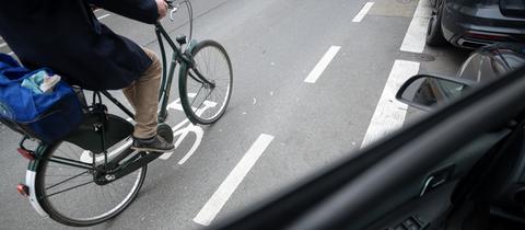 Ein Fahrradfahrer fährt an einer geöffneten Autotür vorbei.
