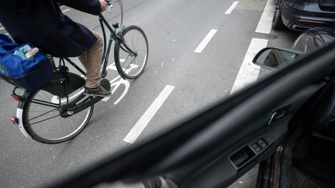 Ein Fahrradfahrer fährt an einer geöffneten Autotür vorbei.