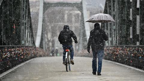 Radfahrer und Fußgänger bei Schneefall auf einer Brücke