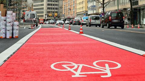 Ein rot markierter Radweg auf einer Straße vor der Frankfurter Skyline.