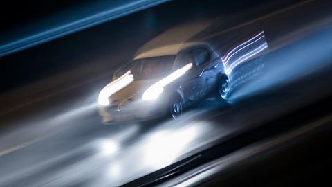 Ein schnell fahrendes Auto mitten im Bild - sowohl Auto als auch Hintergrund sind unscharf aufgrund der Bewegungsunschärfe.