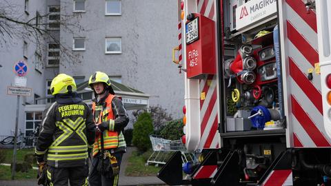Zwei Feuerwehrmänner stehen vor einem Wohnhaus in Raunheim (Groß-Gerau)