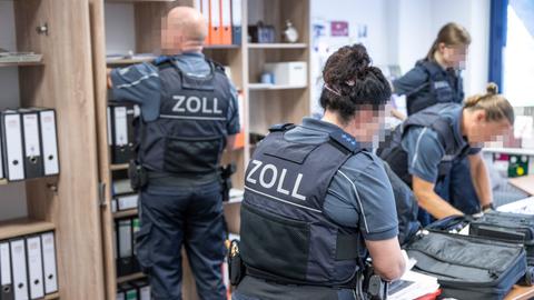 Vier Beamte des Zoll durchsuchen ein Büro