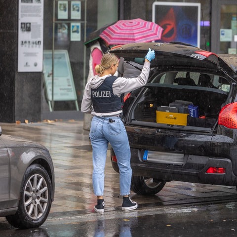 Eine Ermittlerin räumt nach der Razzia Beweisstücke in den Kofferaum eines Kleinwagens.