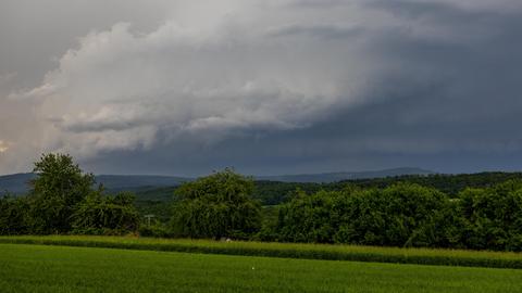 Regenwolken am Himmel, unten grüne Wiese