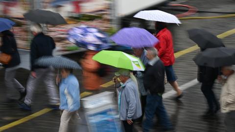 Menschen gehen mit Regenschirmen durch den Regen