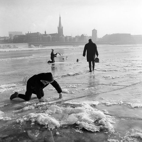 Auf einem zugefrorenen Fluss sind mehrere Menschen zu sehen.