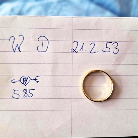 Goldener Ring liegt auf einem linierten Blatt, auf dem "W D 21.2.53" und "585" in Handschrift geschrieben steht.