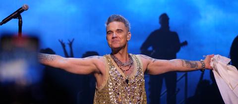 Robbie Williams in Glitzerkostüm auf der Bühne