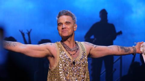 Robbie Williams in Glitzerkostüm auf der Bühne