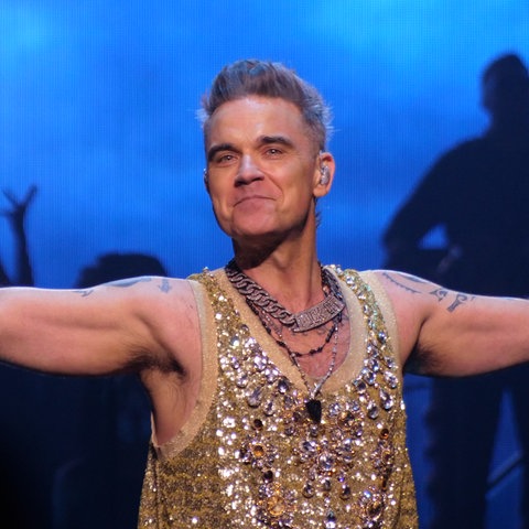 Robbie Williams in Glitzerkostüm auf der Bühne