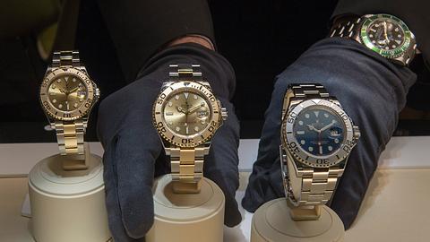 Behandschuhte Hände ordnen goldene Rolex-Uhren in einem Schaufenster.
