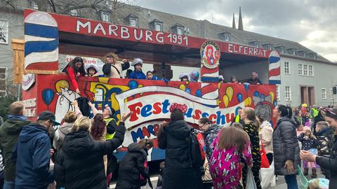 Motivwagen des Elferrats beim Rosenmontagsumzug in Marburg, kostümierte Zuschauer stehen davor