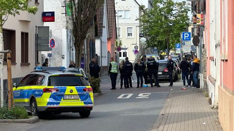 Polizei und Zeugen stehen auf einer abgesperrten Straße am Tatort in Rüsselsheim.