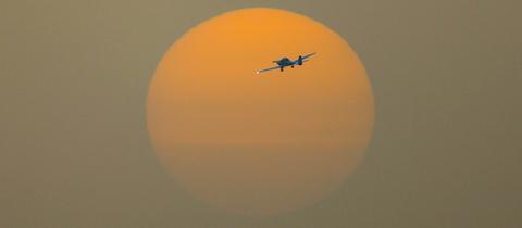 Einmotoriges Flugzeug im Sonnenuntergang, Himmel leuchtet orange-gelb