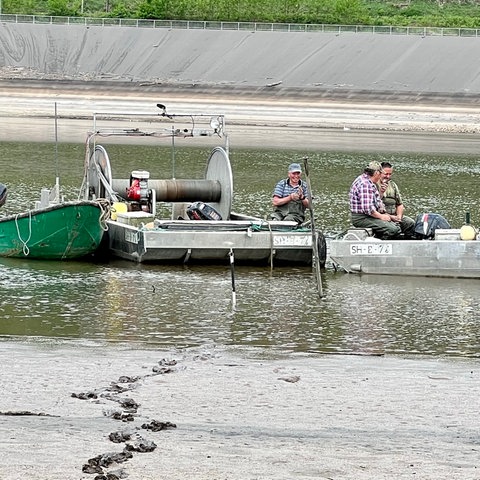 Boote mit Männern auf einer Wasserfläche.