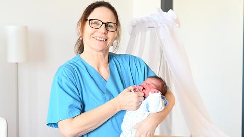 Krankenschwester hält Baby im Arm