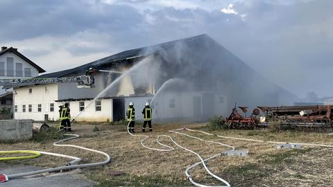 Feuerwehrleute löschen die noch qualmende Scheune.