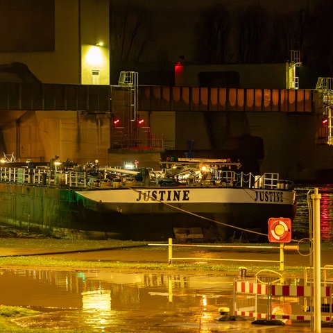 Ein Schiff mit der Aufschrift "Justine" im Dunkeln an einer Schleusenanlage.