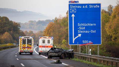 Auf einem Standstreifen an einer Atuobahn steht ein zerstörtes Auto; das Dach ist schon ab. Schilder zeigen, dass es nach Schlüchtern geht.