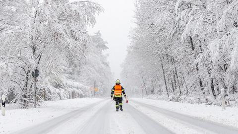 Ein Feuerwehrmann steht am Großen Feldberg im Schnee.