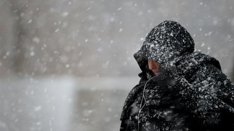 Eine Passantin zieht sich bei Schneefall die Kapuze über den Kopf