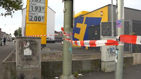 Vor einer Tankstelle hängt ein rot-weiß-gestreiftes Band mit der Aufschrift "Polizeiabsperrung".