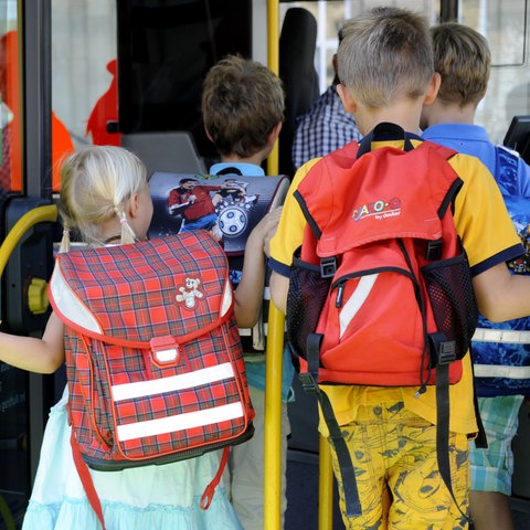 Kinder steigen in einen Schulbus