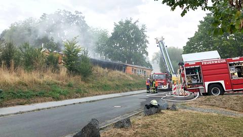 Feuerwehrauto und -leute vor der Schule stehend, aus der es raucht.