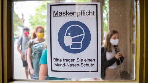 Schüler mit Masken vor einem Hinweisschild zur Maskenpflicht
