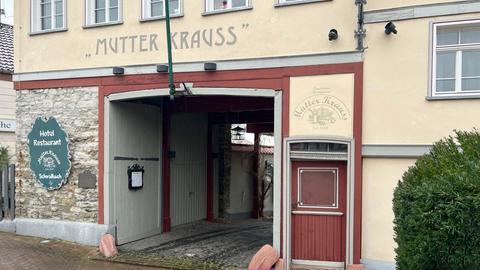 Die Hofeinfahrt eines alten Fachwerkgebäudes mit Sicht in den Innenhof. Links neben der Einfahrt hängt ein Schild mit der Aufschrift "Mutter Krauss". 