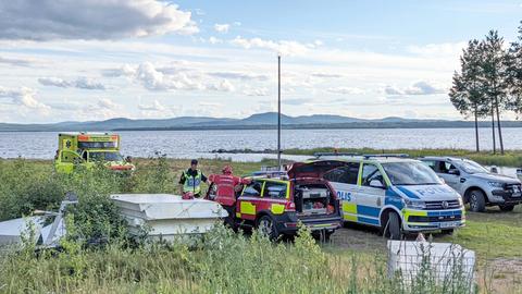 Einsatzkräfte der Polizei und Rettung an dem Ufer eines großen Sees.