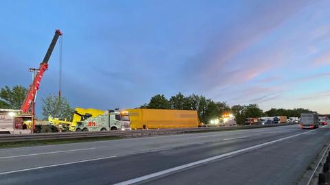 Ein Kran steht auf der gesperrten Autobahn an einem langen Lastwagen