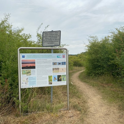 Ein Hinweisschild steht am Ufer des Teufelsee