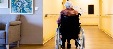 Eine ältere Frau sitzt im Rollstuhl, sie ist alleine.