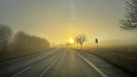 Sonnenaufgang mit Nebelschwaden und Straße