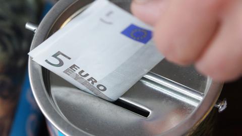 Ein Fünf-Euro-Schein wird in Witten in eine Spendendose gesteckt.