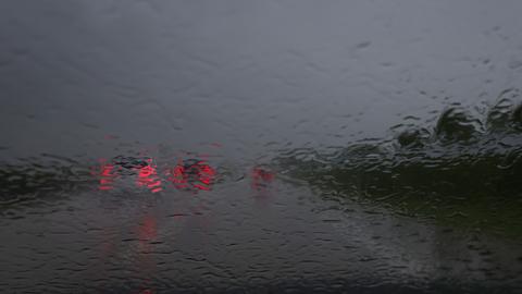 Blcik aus einer Windschutzscheibe eines Autos auf einer Straße, die davor fahrenden Autos sind kaum zu sehen vor lauter Regen
