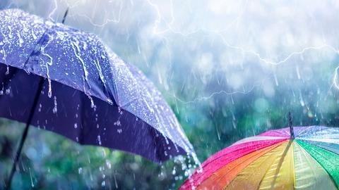 Nahaufnahme zweier Regenschirme(einer blau,einer bunt) bei sehr starkem Regen