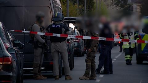 Polizisten stehen in einer abgesperrten Straße.