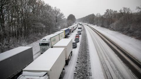 Lastwagen stauen sich auf einer Autobahn im Schnee