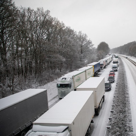 Lastwagen stauen sich auf einer Autobahn im Schnee