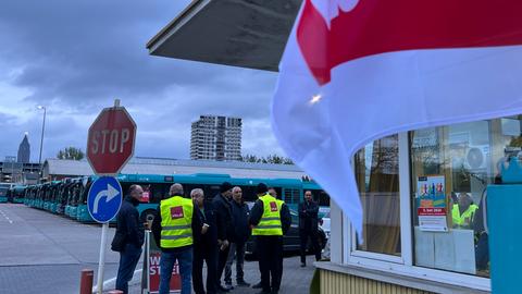 Busfahrer mit Verdi-Warnwesten stehen vor den stillstehenden Bussen im Frankfurter Depot.