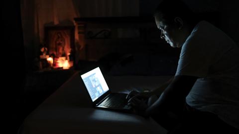 Mann beugt sich im Dunkeln über sein Laptop