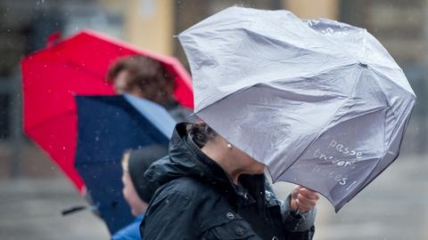 Menschen mit Regenschirm im Wind