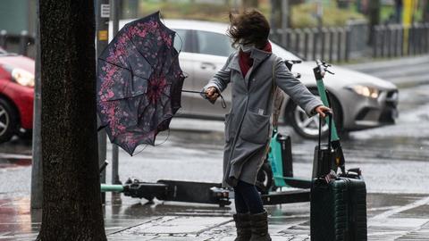Eine Frau kämpft mit dem stürmischen Wind, während sie versucht, in der Frankfurter Innenstadt eine Straße zu überqueren. 