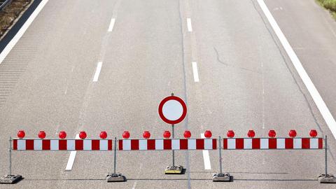 Eine leere dreispurige Autobahn aus der Vogelperspektive fotografiert. Vorne stehen Absprerrgitter und ein "Einfahrt verboten-Schild".